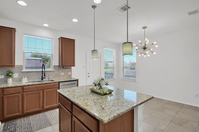Kitchen with a kitchen island, a sink, visible vents, and decorative backsplash | Image 16