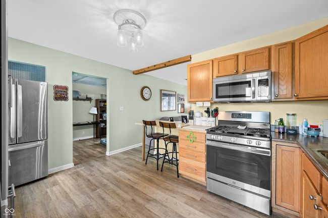 kitchen featuring dark countertops, brown cabinetry, stainless steel appliances, light wood finished floors, and baseboards | Image 18