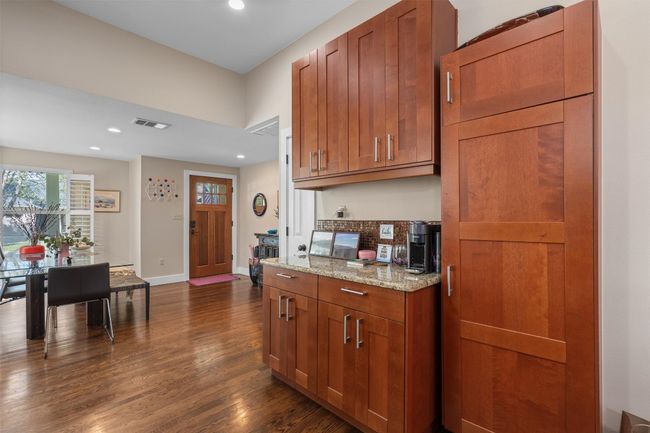 Kitchen featuring light stone countertops, dark wood-type flooring, brown cabinetry, and visible vents | Image 8