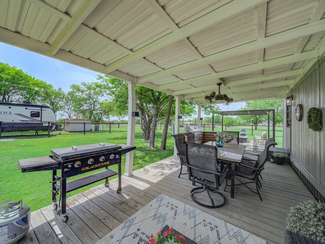 Wooden deck featuring grilling area, outdoor dining area, house two. | Image 29