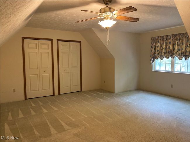 Additional living space featuring a textured ceiling, light colored carpet, ceiling fan, and vaulted ceiling | Image 18