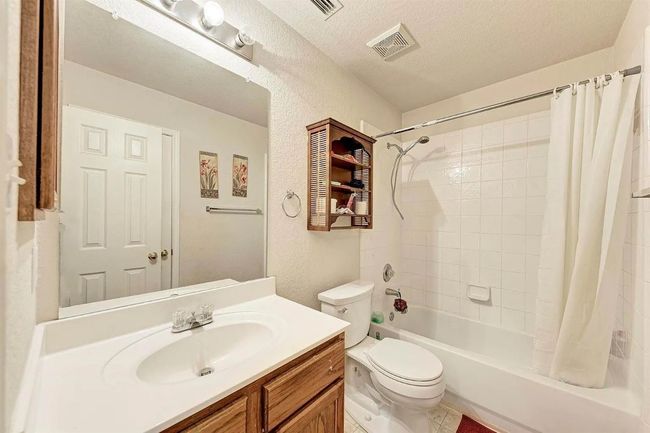 Full bath with shower / tub combo with curtain, vanity, a textured wall, and a textured ceiling | Image 6