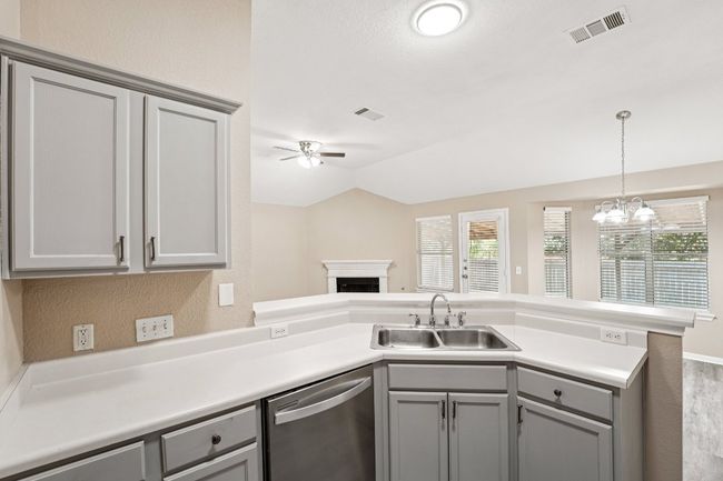 Kitchen with a peninsula, gray cabinets, dishwasher, light countertops, and pendant lighting | Image 12
