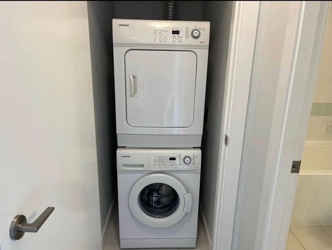 Laundry room featuring baseboards, light tile patterned floors, stacked washer and clothes dryer, and laundry area | Image 13