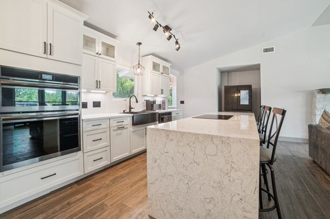 Chef's kitchen with expansive waterfall quartz island and breakfast bar | Image 8