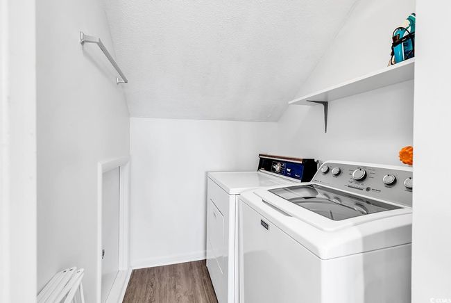 Laundry area featuring laundry area, a textured ceiling, baseboards, wood finished floors, and washer and clothes dryer | Image 22