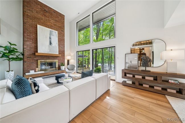 Living area featuring a high ceiling, a brick fireplace, and light wood-style floors | Image 19