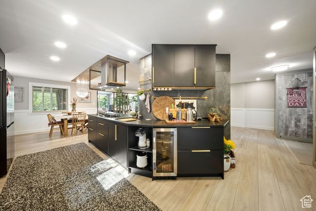 Bar with wine cooler, light wood-style flooring, island range hood, recessed lighting, and wainscoting | Image 7