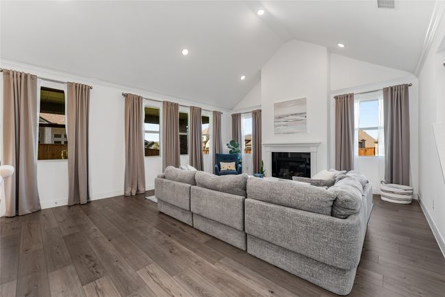 Living area with high vaulted ceiling, a glass covered fireplace, dark wood-style floors, and recessed lighting | Image 10