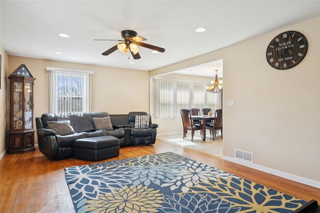Living area with visible vents, baseboards, recessed lighting, ceiling fan with notable chandelier, and wood finished floors | Image 11