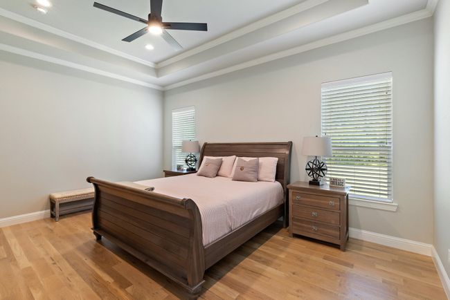 Bedroom with baseboards, crown molding, light wood-type flooring, and a raised ceiling | Image 16