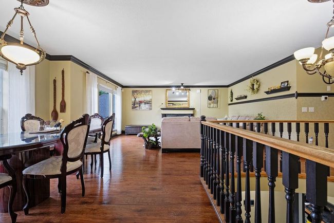 Dining space with ornamental molding, a chandelier, and wood finished floors | Image 8