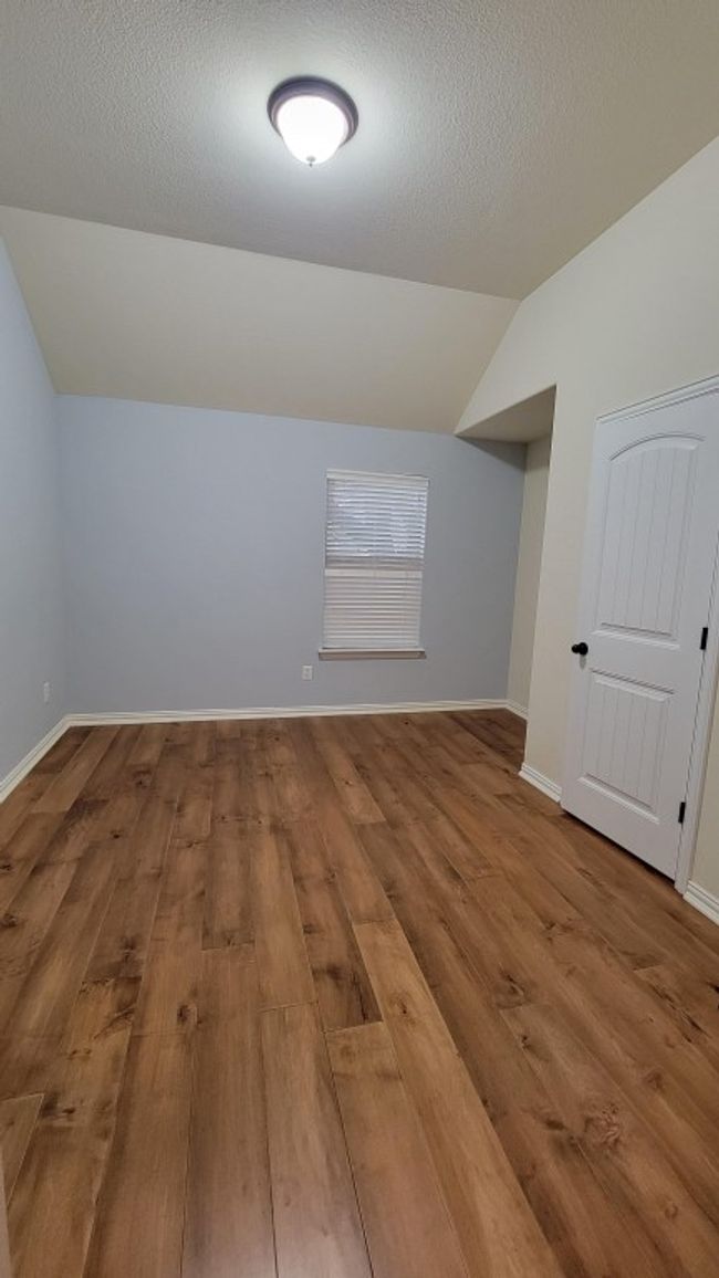 Bonus room featuring vaulted ceiling, wood finished floors, baseboards, and a textured ceiling | Image 13