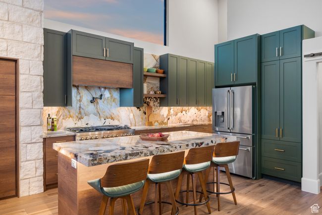 Kitchen with stainless steel fridge, tasteful backsplash, a kitchen island, a breakfast bar area, and a high ceiling | Image 27