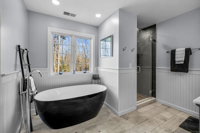 Remodeled full bath offers a spa-like retreat after a day of work or play. Tile floor, bead-board trim, dual sink vanity, soaking tub, walk-in shower, private toilet w/pocket door. | Image 18