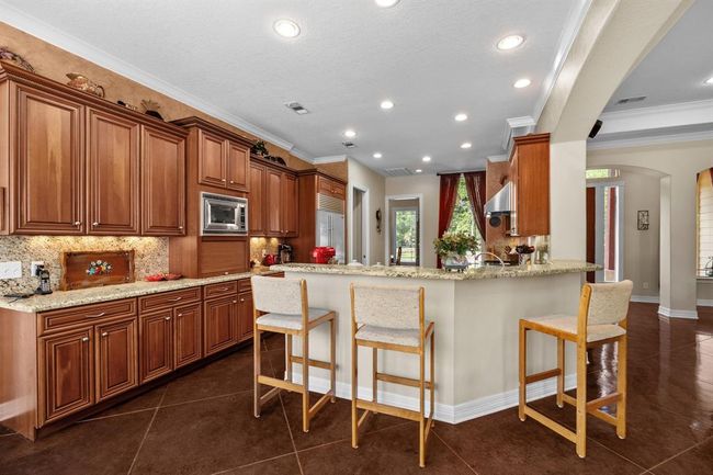 Granite-topped peninsula offers casual seating for three, generous prep space, and seamless sightlines into the family room and dining nook. | Image 15