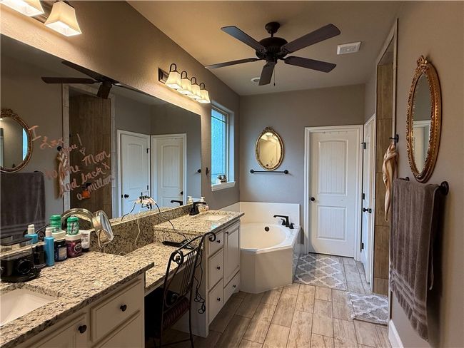 Bathroom featuring a garden tub, two vanities, ceiling fan, and wood finish floors | Image 13