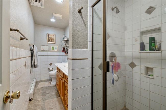 Bathroom with visible vents, baseboard heating, a shower stall, vanity, and toilet | Image 21