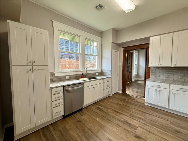 Kitchen with stainless steel dishwasher, tasteful backsplash, wood finished floors, and white cabinets | Image 4