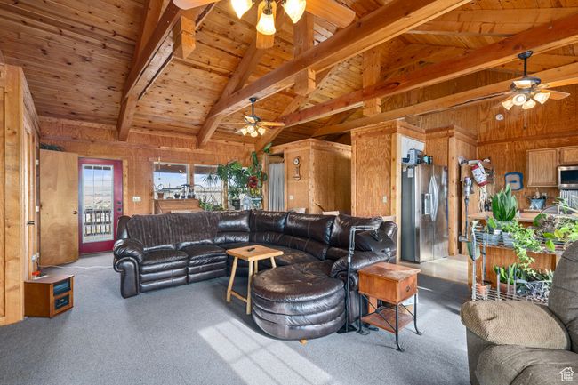 Carpeted living room featuring beamed ceiling, high vaulted ceiling, wooden ceiling, and wood walls | Image 25