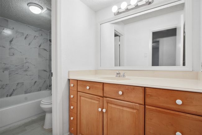 Bathroom with toilet, a textured ceiling, bathing tub / shower combination, and vanity | Image 9