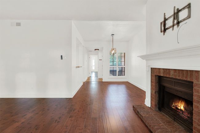 Unfurnished living room featuring a fireplace and dark wood finished floors | Image 7