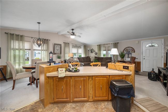 Kitchen featuring a ceiling fan, a kitchen island, light countertops, crown molding, and a chandelier | Image 26