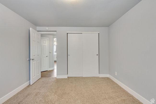 Unfurnished bedroom with carpet flooring, baseboards, and a closet | Image 11