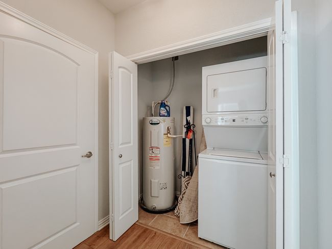 Laundry area located in hallway featuring stacked washer / dryer, laundry area, water heater, and light wood-style flooring | Image 18