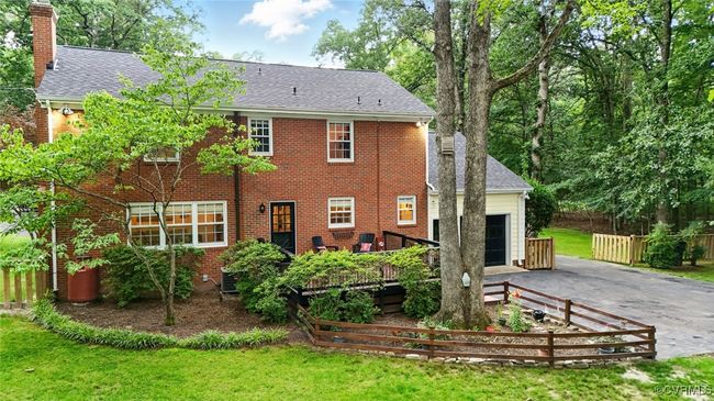 Rear view of house with asphalt driveway, a garage, a chimney, brick siding, and a shingled roof | Image 5