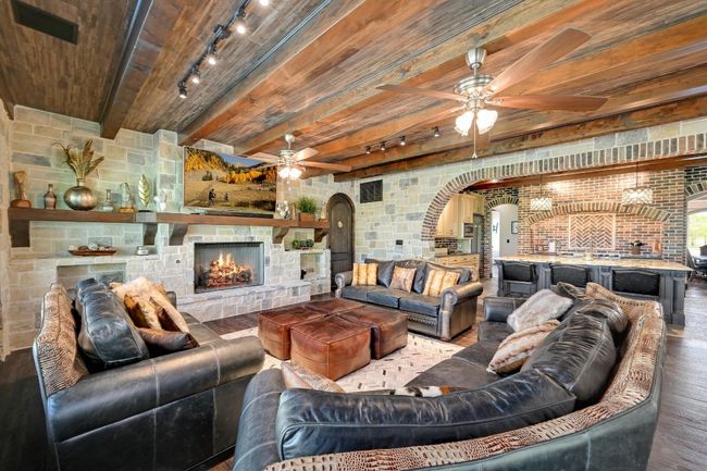 Living room with ceiling fan, rail lighting, arched walkways, and wood ceiling | Image 13