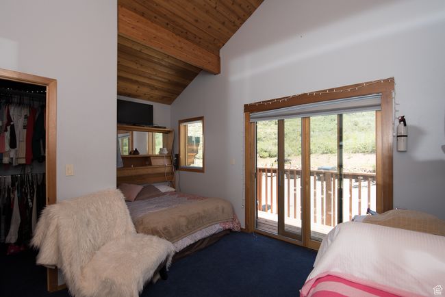 Carpeted bedroom with high vaulted ceiling, a closet, wood ceiling, beam ceiling, and access to exterior | Image 77