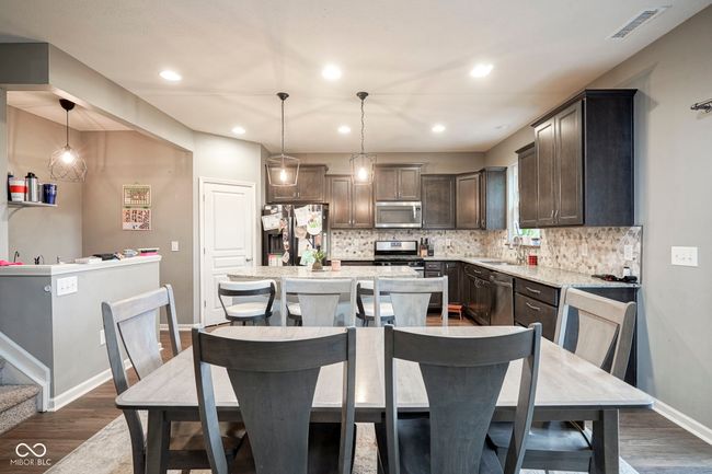kitchen featuring stainless steel appliances, dark wood-style floors, dark brown cabinets, backsplash, and a kitchen island | Image 14