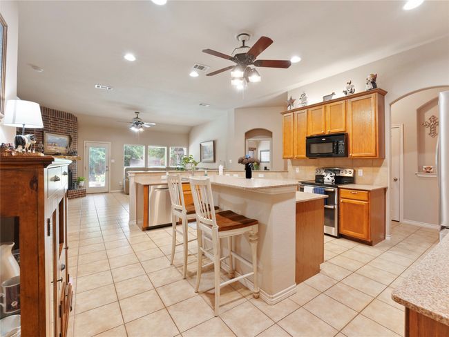 Kitchen with stainless steel appliances, ceiling fan, arched walkways, light tile patterned flooring, and recessed lighting | Image 10