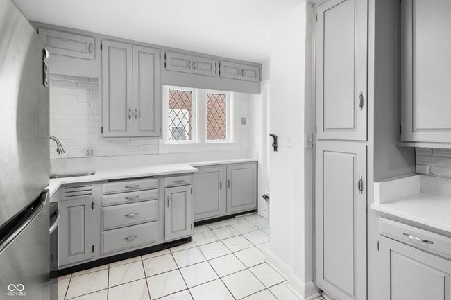 kitchen with freestanding refrigerator, light countertops, gray cabinetry, and a sink | Image 22