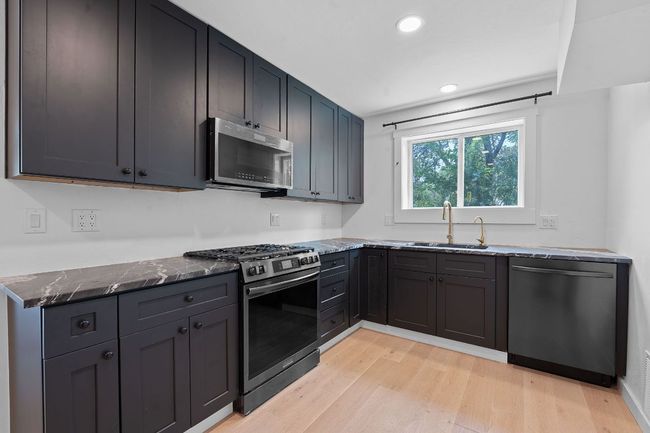 Kitchen featuring appliances with stainless steel finishes, dark stone counters, light wood-style floors, and recessed lighting | Image 8