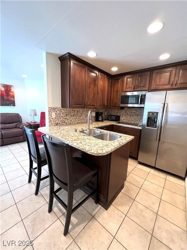 Kitchen with a sink, tasteful backsplash, appliances with stainless steel finishes, a peninsula, and light tile patterned floors | Image 19
