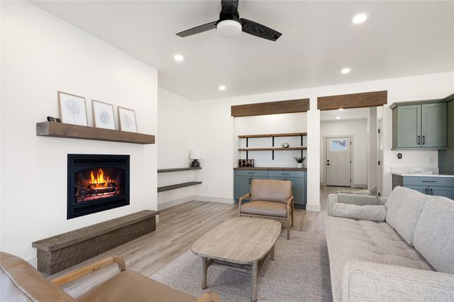Living room featuring light wood finished floors, a warm lit fireplace, a ceiling fan, and recessed lighting | Image 6