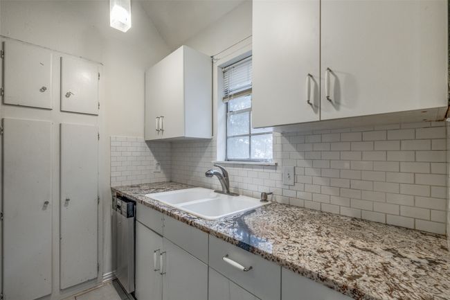Kitchen featuring dishwasher, decorative backsplash, white cabinets, light stone counters, and vaulted ceiling | Image 9
