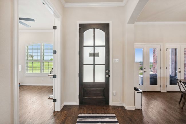 Entrance foyer featuring crown molding, baseboards, arched walkways, and dark wood-style flooring | Image 6