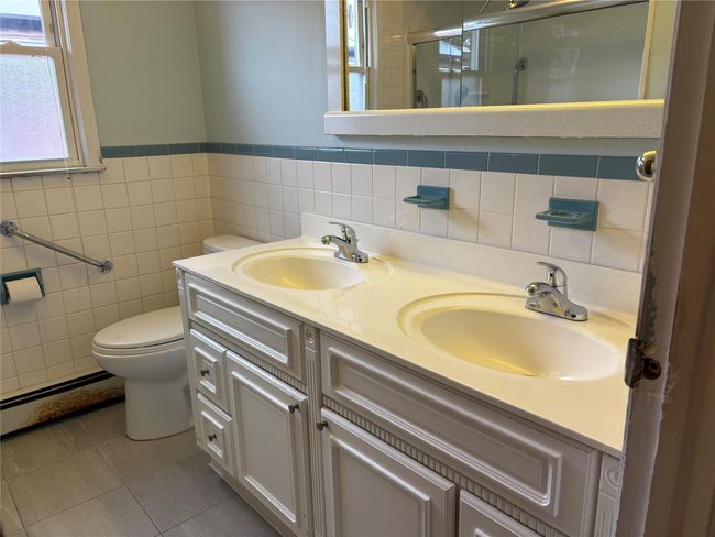 Bathroom with a sink, toilet, a shower stall, and a baseboard radiator | Image 6
