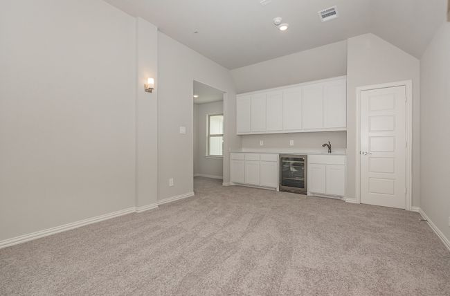 Indoor wet bar featuring wine cooler, vaulted ceiling, light carpet, and baseboards | Image 21