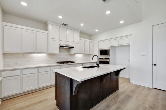 Kitchen featuring backsplash, white cabinetry, a kitchen island with sink, light wood-style floors, and recessed lighting | Image 6