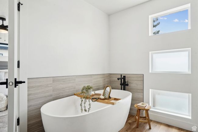 Bathroom with wainscoting, a freestanding tub, wood finished floors, and tile walls | Image 20