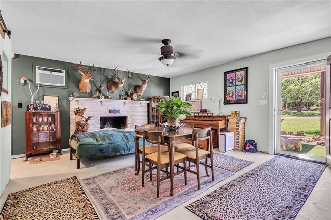 Dining space featuring a wall mounted AC, ceiling fan, plenty of natural light, a brick fireplace, and a textured ceiling | Image 31