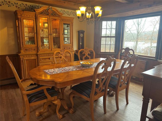 Dining area with a wainscoted wall, a notable chandelier, and light wood-style flooring | Image 8