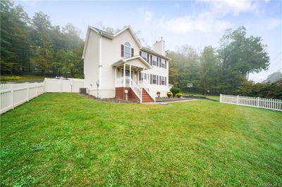 Another view of the front exterior and yard. The property features a white fencing. | Image 2