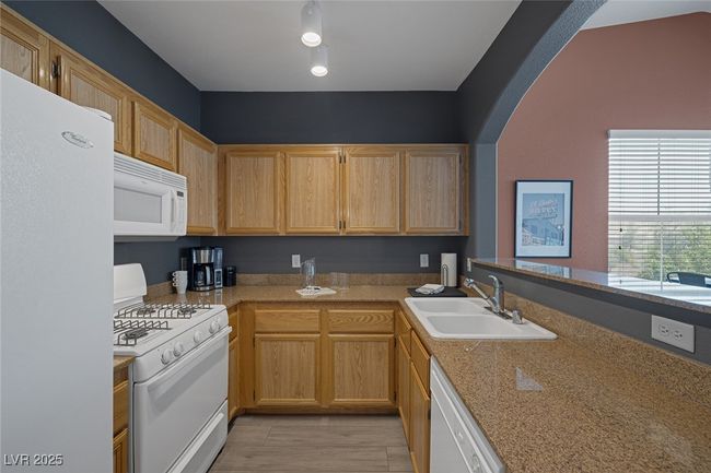 Kitchen with a sink, light countertops, white appliances, and arched walkways | Image 9