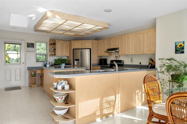 Spacious kitchen features stainless steel appliances, a sizeable island, and a cozy breakfast nook—perfect for gathering and entertaining. | Image 4