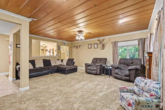 Living area with baseboards, carpet, crown molding, and wood ceiling | Image 7